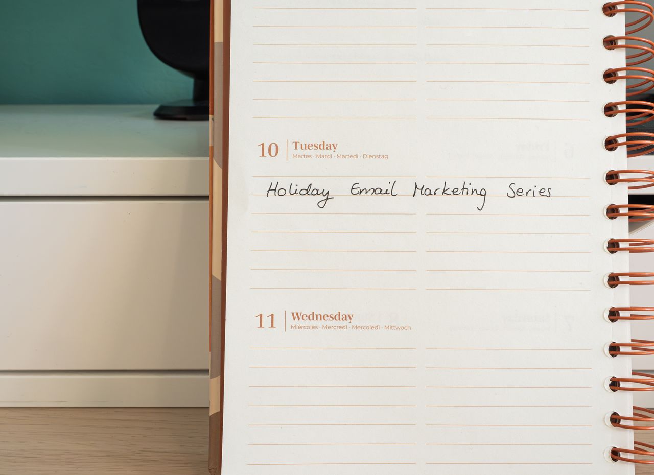 why-choose-us Planner open on a desk with handwritten Holiday Email Marketing Series note.